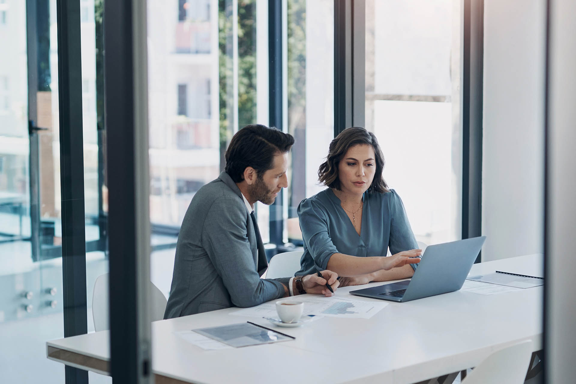Business man, woman and laptop in discussion in team, brainstorming or proposal for b2b collaboration. People, computer or meeting with paperwork for financial strategy, idea or negotiation in office